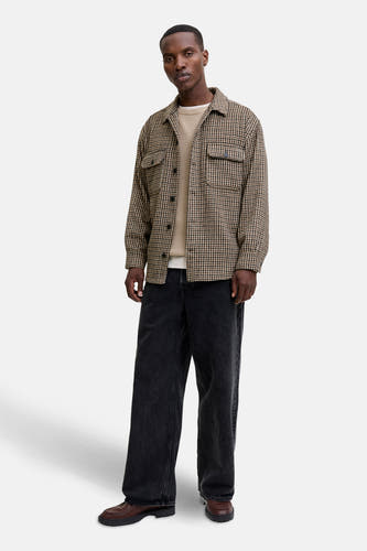 Chemise brune à longues manches d'ORIGINALS BY JACK & JONES, avec un motif à carreaux, portée sur une chemise et un pantalon noir large.