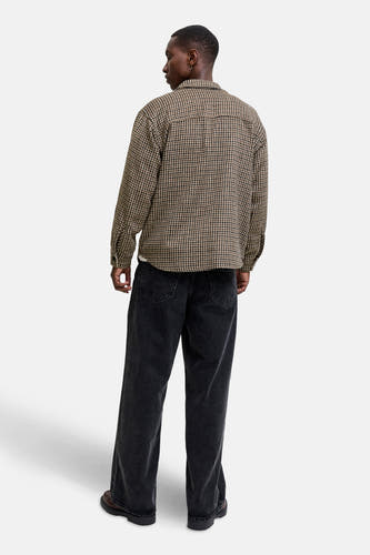 Chemise brune à longues manches d'ORIGINALS BY JACK & JONES, avec un motif houndstooth et des jeans noirs.