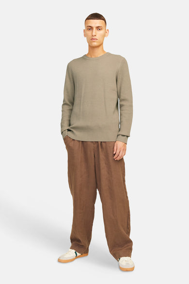 Pull beige avec col rond de CORE BY JACK & JONES, avec des manches longues et porté avec un pantalon de lin marron et des chaussures crème.