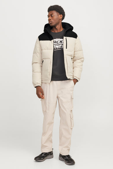 Manteau court écru de CORE BY JACK & JONES, avec des détails noirs et porté avec un pantalon cargo beige et des baskets noires.
