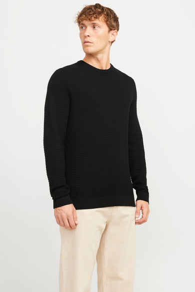 Sweat-shirt noir à col rond de CORE BY JACK & JONES, avec une texture côtelée horizontale, porté avec un pantalon beige.