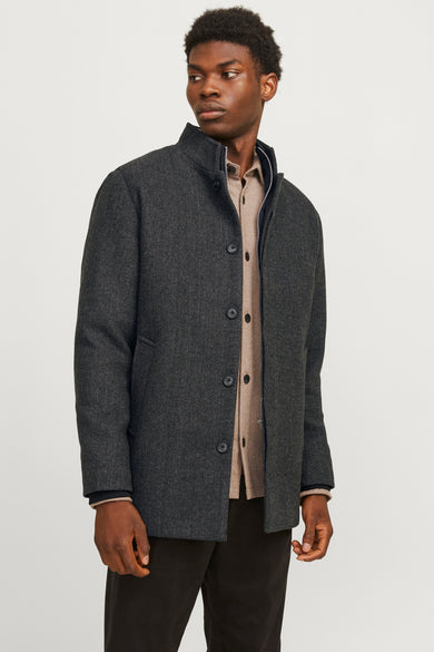 Manteau gris long de PREMIUM par JACK & JONES, avec une fermeture à boutons sur un chemisier beige et un pantalon noir.