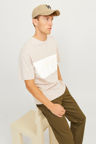T-shirt beige à manches courtes de CORE BY JACK & JONES, porté avec un pantalon vert olive et une casquette avec logo.
