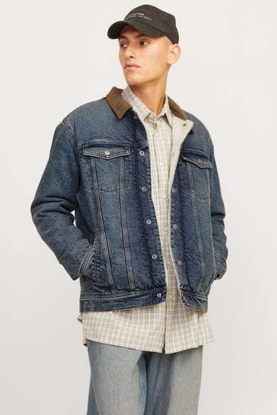 Manteau de denim bleu marine de JACK & JONES JEANS INTELLIGENCE, avec une collet marron et porté avec des jeans larges et des bottines beige.