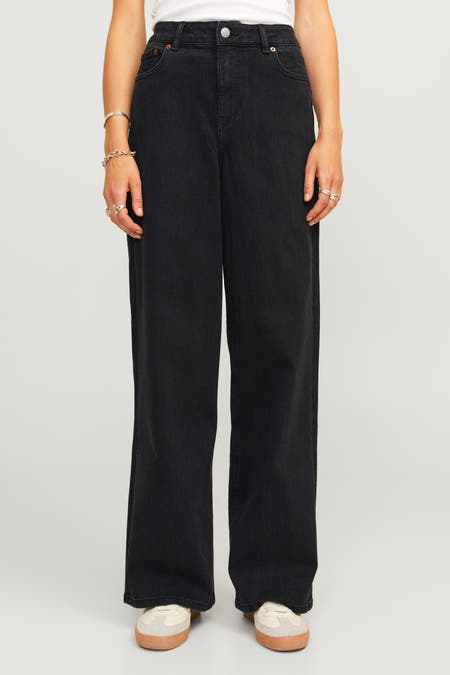 Jean en denim noir de JJXX, avec des jambes larges et des bijoux argentés autour des poignets.