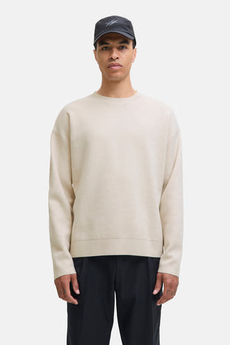 Pull-over beige avec col rond de PREMIUM par JACK & JONES, porté avec un chapeau noir et une pantalon noir.