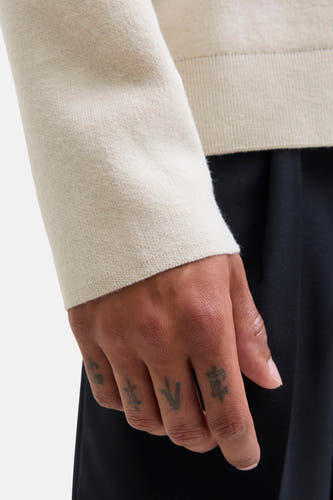 Sweat-shirt beige avec col rond de PREMIUM by JACK & JONES, gros plan sur la manche et la main tatouée.