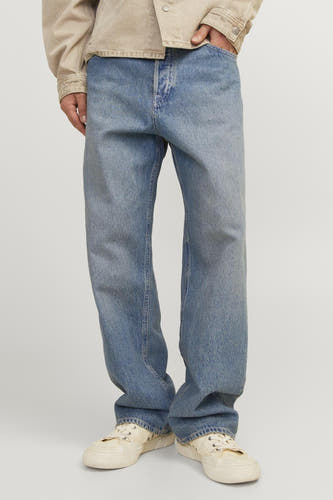 Jeans bleu ample de JACK & JONES JEANS INTELLIGENCE, avec un délavage clair et des baskets beiges.