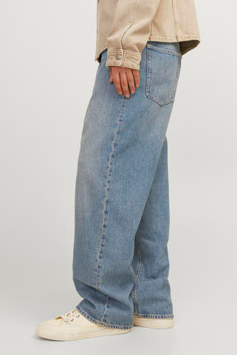 Jeans larges en denim bleu moyen de JACK & JONES JEANS INTELLIGENCE, avec délavage vintage et baskets beiges.