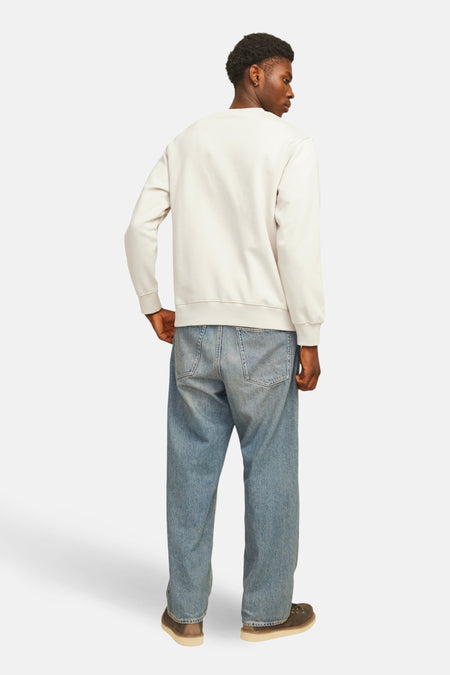 Man met sweater en wijde jeans van achteren gezien.