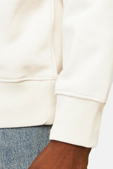 Off-white sweater met geribde manchetten en jeans.