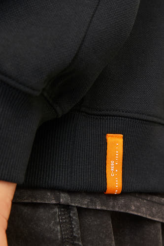 Gilet noir de CORE BY JACK & JONES avec une petite étiquette de marque orange sur le côté.