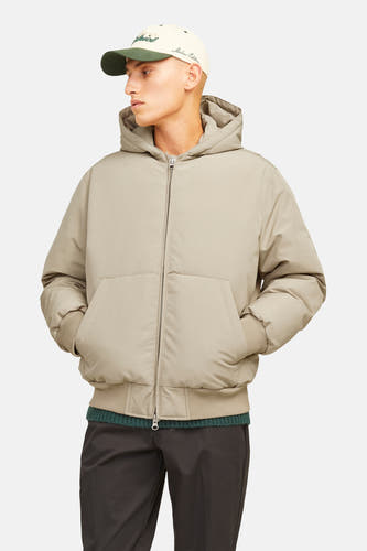 Veste courte beige de CORE BY JACK & JONES avec motif à carreaux subtil, capuche, fermeture éclair, poignets côtelés et poches latérales, portée par un mannequin avec une casquette.