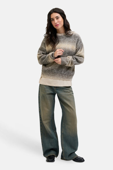 Gilet rond beige de JJXX porté sur un shirt crème et des jeans larges avec effet ombre.