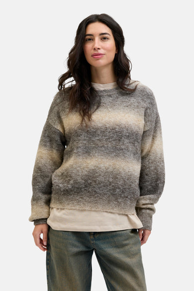 Gilet rond beige de JJXX, avec des rayures et porté sur un T-shirt crème.