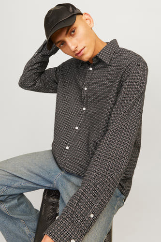 Chemise brune à longues manches d'ORIGINALS BY JACK & JONES, avec un motif de carreaux géométriques et portée avec une casquette noire et des jeans bleus.