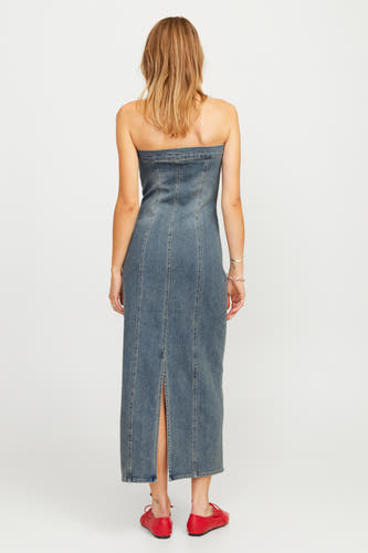 Mouwloze blauwe denim jurk van JJXX, met een split aan de achterkant en rode schoenen.
