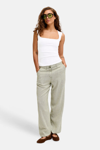 Witte top zonder mouwen van JJXX, gedragen met gestreepte broek en bruine schoenen.
