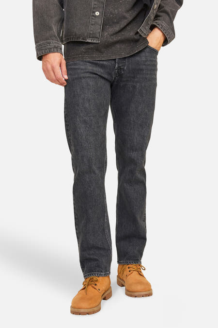 Jean tapered noir de JACK & JONES JEANS INTELLIGENCE, avec un manteau en denim coordonné et des chaussures brunes.