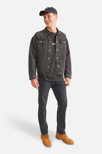 Jean tapered noir de Jack & Jones, associé à une veste en cuir noire, un T-shirt et des bottes militaires brunes.