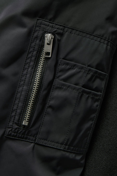 Manteau court noir de JJXX, avec une poche à fermeture éclair et des détails en boutons.