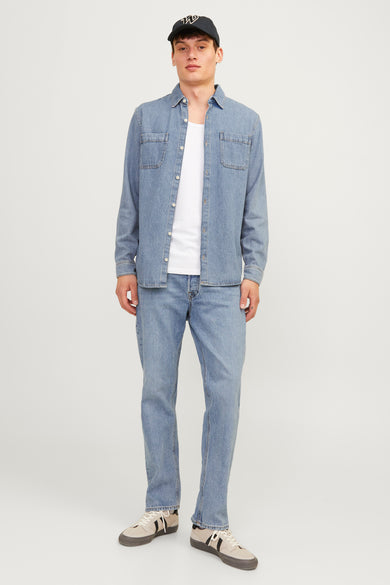 Jean tapered bleu clair de JACK & JONES JEANS INTELLIGENCE, porté avec un t-shirt blanc et une chemise en denim.