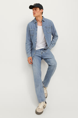 Jean tapered bleu clair de JACK & JONES JEANS INTELLIGENCE, associé à une chemise en denim et un T-shirt blanc.