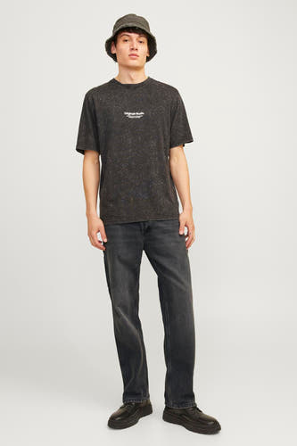 Jean délavé noir de JACK & JONES JEANS INTELLIGENCE, avec un lavage foncé et une apparence décontractée, porté avec un T-shirt et un chapeau.