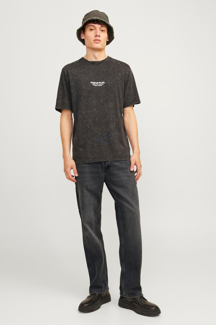 Jean délavé noir de JACK & JONES JEANS INTELLIGENCE, avec un lavage foncé et une apparence décontractée, porté avec un T-shirt et un chapeau.