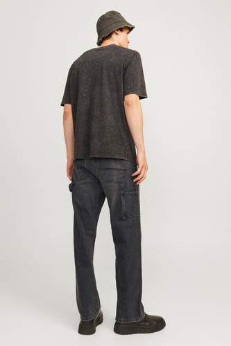 Jean délavé noir de JACK & JONES JEANS INTELLIGENCE, avec des poches à outils, associé à un T-shirt noir et un chapeau bucket.