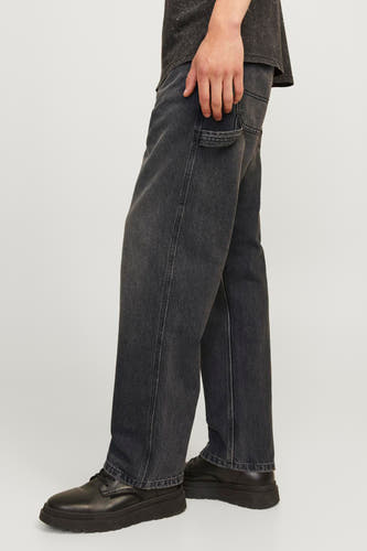 Jean en denim noir large de JACK & JONES JEANS INTELLIGENCE, avec une poche à outils, associé à des chaussures noires en cuir avec une semelle épaisse.