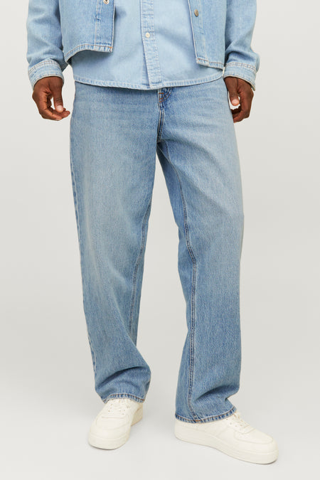 Jean coupe ample en denim bleu clair de JACK & JONES JEANS INTELLIGENCE, avec une veste en jean assortie et une casquette rouge.