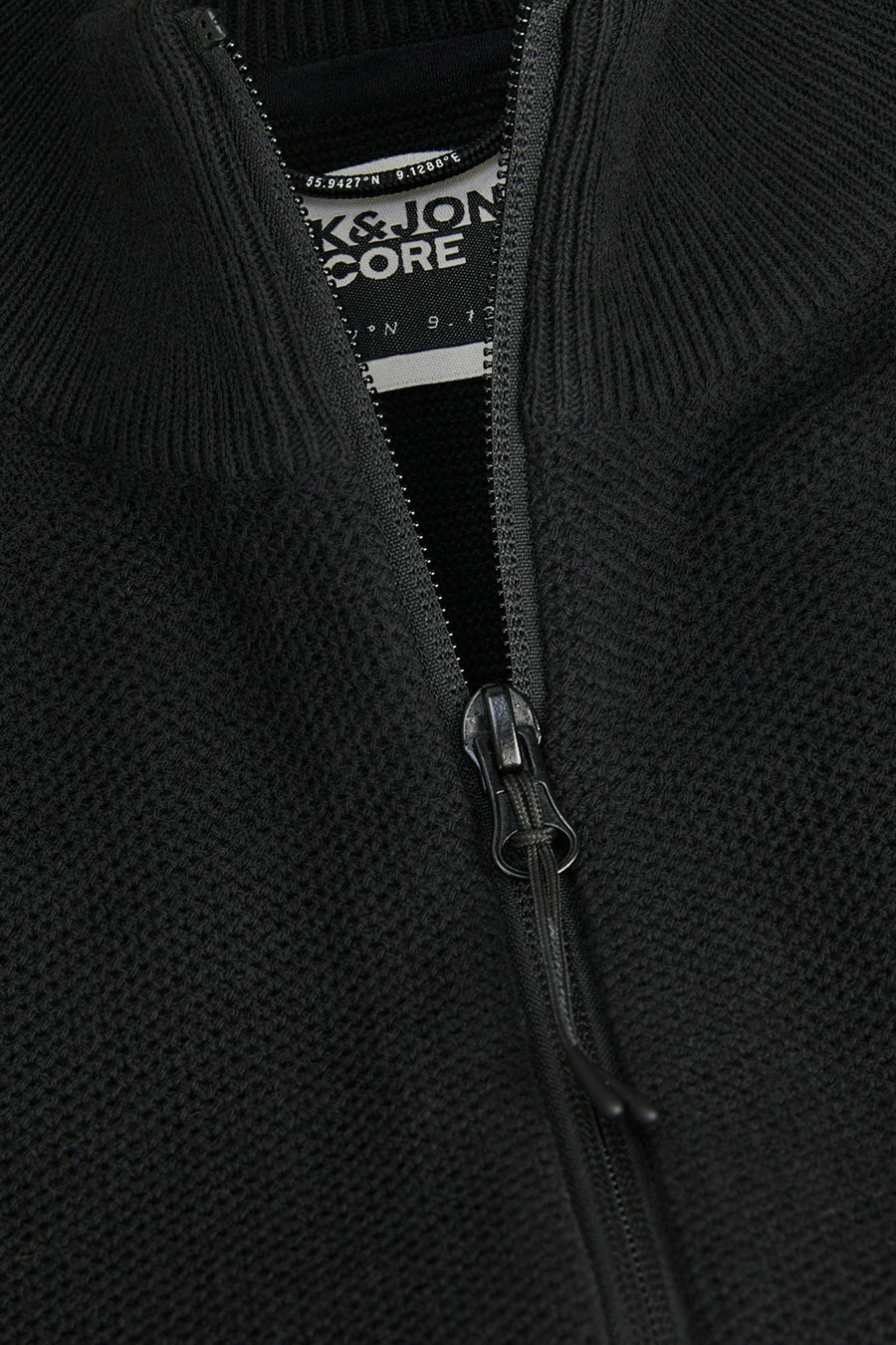Gilet noir de CORE BY JACK & JONES, avec une fermeture éclair visible et un étiquette.