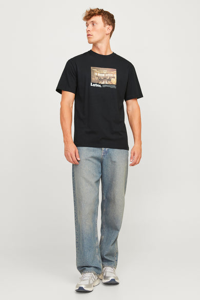 T-shirt noir à manches courtes d'ORIGINALS BY JACK & JONES, avec imprimé photo, porté avec des jeans bleus et des baskets.