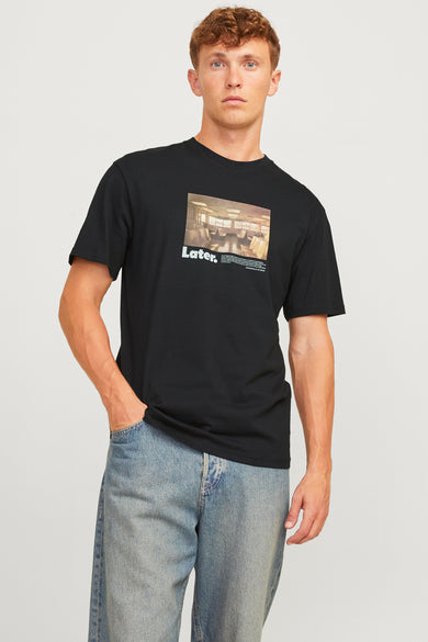 T-shirt noir à manches courtes d'ORIGINALS BY JACK & JONES, avec une impression et porté avec un jean bleu.