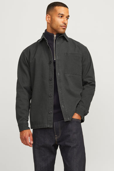 Chemise verte à manches longues de la division Royal Denim, avec une poche poitrine et portée sur un pull et des jeans foncés.