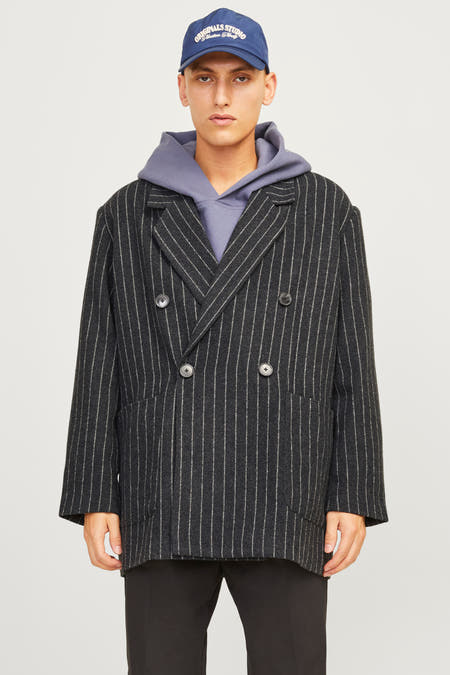 Blazer noir d'ORIGINALS BY JACK & JONES, avec des rayures de craie, associé à une hoodie grise, un pantalon noir et des baskets crème.