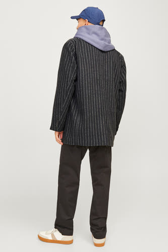 Zwarte blazer van ORIGINALS BY JACK & JONES, met krijtstrepen, gecombineerd met een grijze hoodie, zwarte broek en crèmekleurige sneakers.