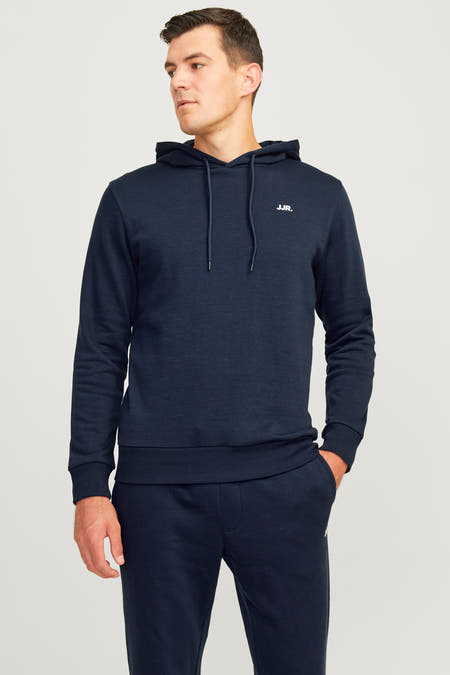 Pull-over bleu avec capuche de JJREBEL, associé à un pantalon de jogging coordonné et des baskets blanches.