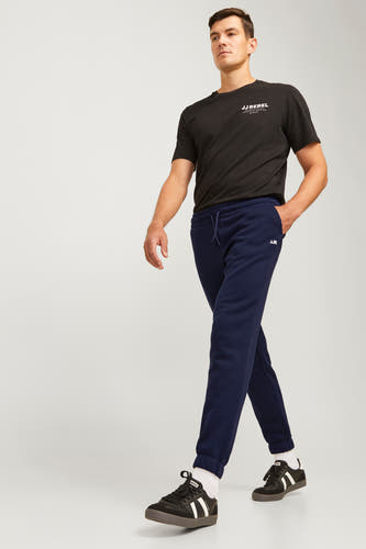 Blauwe joggingbroek van JJREBEL, met elastische tailleband en zichtbare sneakers met witte sokken.
