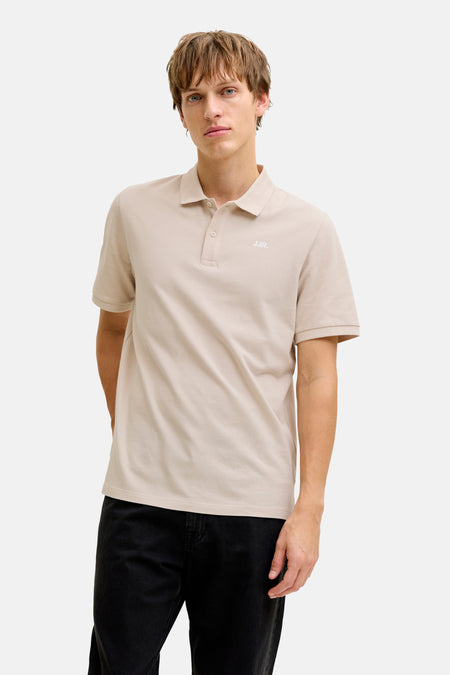 Polo beige de JJREBEL, à manches courtes et porté avec un jean noir.