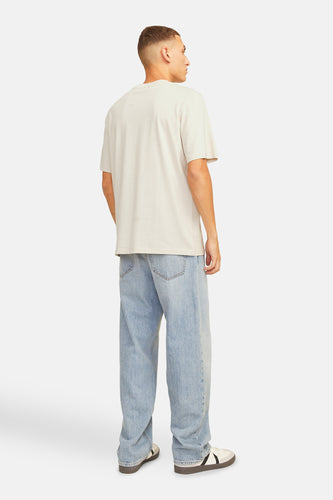 Man in beige T-shirt en blauwe jeans, staand van achteren.