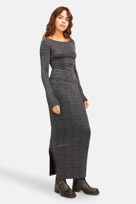 Long manteau d'argent de JJXX, avec une fente sur le côté et porté avec des bottes noires.