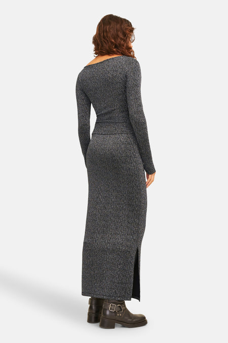 Long manteau argenté de JJXX, avec une fente et porté avec des bottes en cuir à boucles.