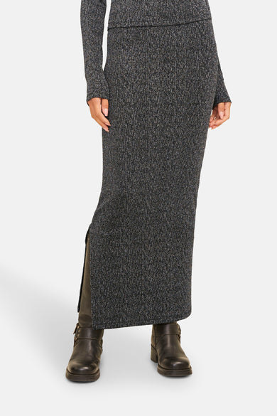 Robe longue en argent de JJXX, avec une fente sur le côté et associée à des bottes noires.