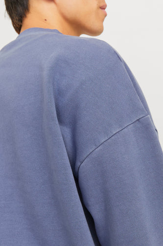 Close-up van de schouder en een gedeelte van het gezicht van een persoon met een blauw-paarse trui.