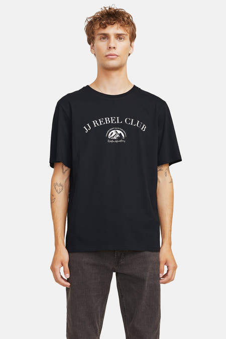 T-shirt noir à manches courtes de JJREBEL, avec une impression blanche sur la poitrine, porté avec un pantalon foncé.