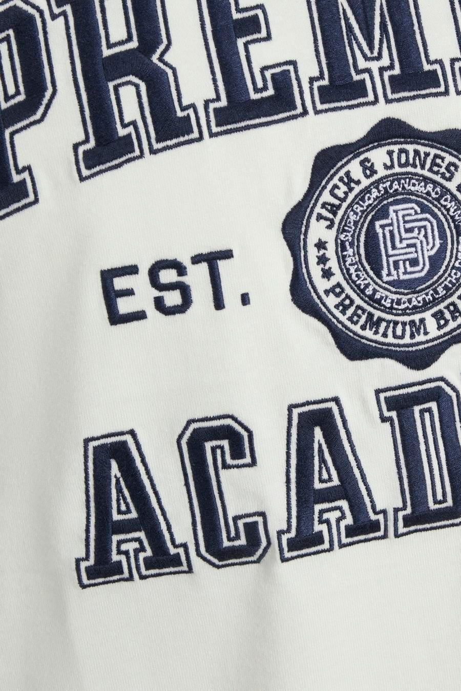 Close-up van een wit kledingstuk met marineblauwe geborduurde tekst en een logo met de tekst "JACK & JONES".