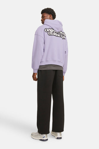 Man met paarse hoodie, zwarte broek en grijze sneakers.