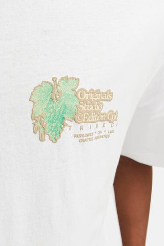 Close-up van een wit T-shirt met een borduurwerk van een druiventros en tekst.